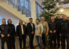 Innenstaatssekretär Sandro Kirchner, Manfred Ländner, MdL und Beschäftigte der Polizeiinspektion Würzburg-Land in Treppenhaus vor Weihnachtsbaum