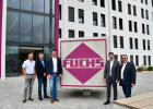 Gruppenfoto mit Staatssekretär Sandro Kirchner und Vertretern von Fuchs Europoles vor Firmenschild