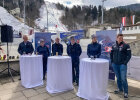 Innenminister Joachim Herrmann und weitere Personen hinter Stehtischen, im Hintergrund Skischanze