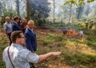 Innenminister Joachim Herrmann und weitere Beteiligte in Beobachtung auf Waldlichtung mit brennendem Feuer