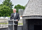 Innenminister Joachim Herrmann hinter Rednerpult neben einem Gebäude der KZ-Gedenkstätte