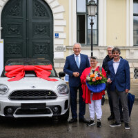 Innenminister Joachim Herrmann mit Gewinnern neben BMW Mini mit Schleife