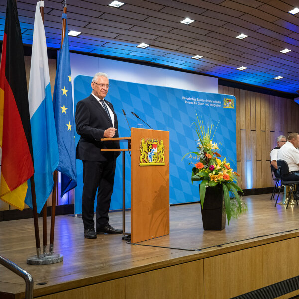 Innen- und Kommunalminister Joachim Herrmann auf Bühne am Rednerpult, im Hintergrund Musikgruppe