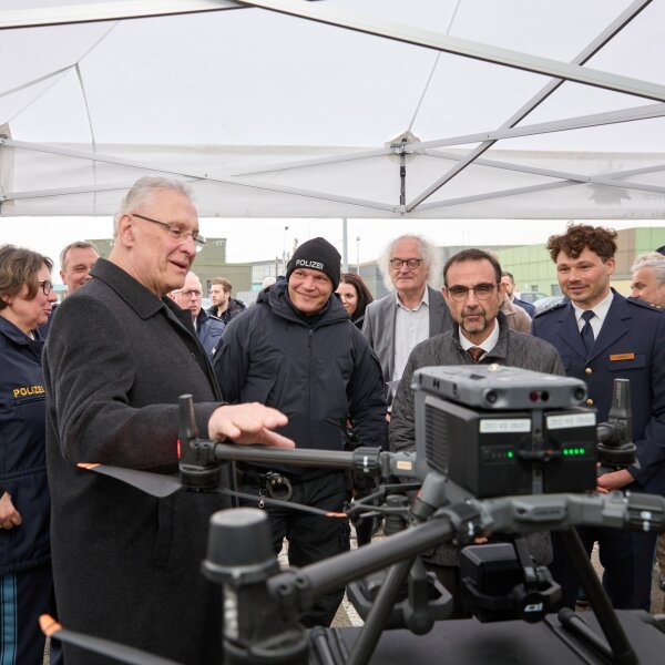 Innenminister Herrmann bei Präsentation mit vielen Menschen, im Vordergrund eine Drohne