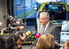 Innenminister Joachim Herrmann bei Pressekonferenz, im Hintergrund Polizeifahrsimulator