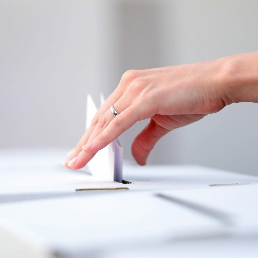 Hand lässt Wahlschein in Wahlurne fallen